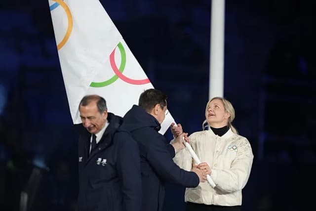 IOC President Kirsty Coventry holding the Olympic flag during an official Olympic ceremony, illustrating the new female-category eligibility policy