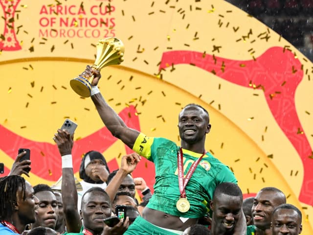 Senegal forward Sadio Mane holds up the Africa Cup of Nations trophy with teammates celebrating after the January 18 final in Rabat — a title CAF stripped away on Tuesday