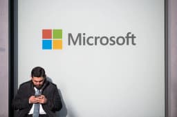 A man uses a phone next to a Microsoft logo at the World Economic Forum in Davos, photographed by Romina Amato for Reuters