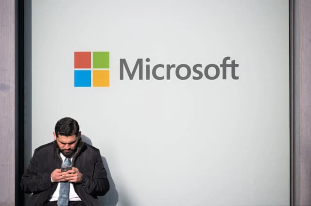 A man uses a phone next to a Microsoft logo at the World Economic Forum in Davos, photographed by Romina Amato for Reuters