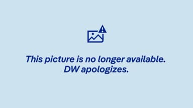 A woman wearing a burkini walks into the water at a public swimming area