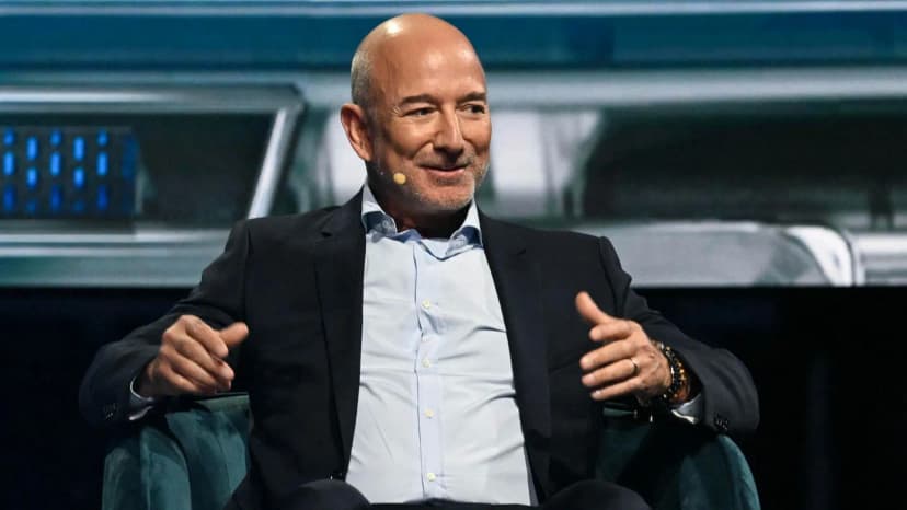 Jeff Bezos speaking at a business forum, gesturing while discussing his vision for AI-driven manufacturing transformation