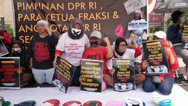 Activists hold posters and household items during a protest demanding legal protection for domestic workers outside parliament in Jakarta, photographed by AP's Tatan Syuflana