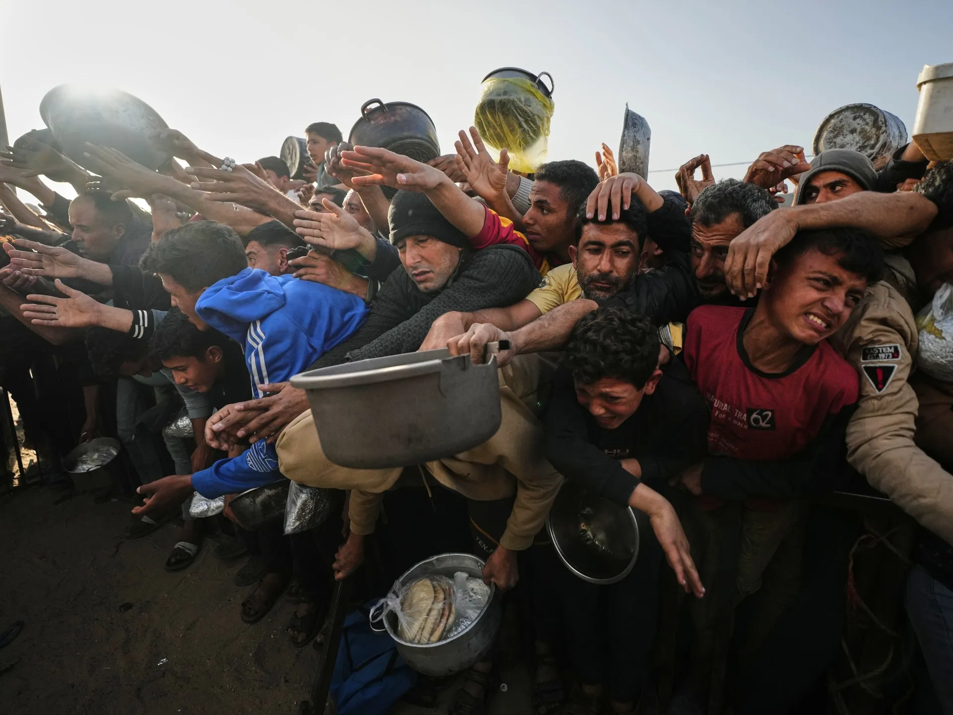 Displaced Palestinians gather with food containers during an aid distribution in Gaza, in an AP photo used by Al Jazeera's report on the 2026 Global Report on Food Crises