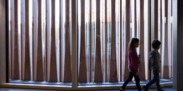 Two young patients walk through the new Zurich children's hospital building, illustrating the institution at the center of the 2025 funding and governance debate.