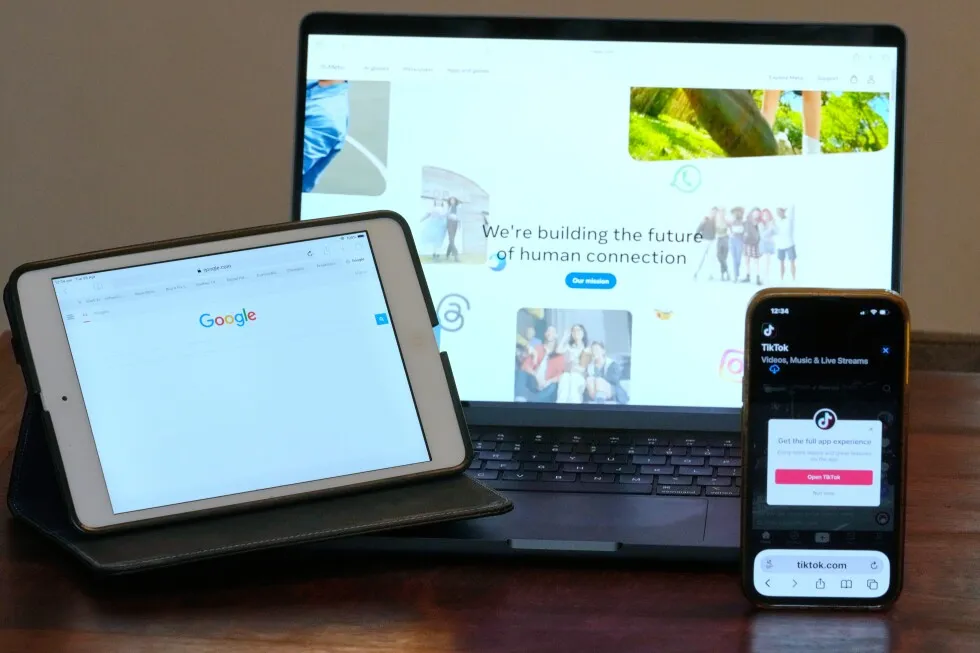 Home pages for Meta, Google and TikTok displayed on devices in Sydney as Australia unveils a proposed levy tied to news-payment deals
