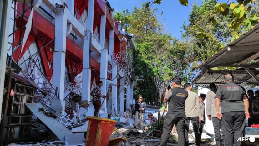 Police officers inspect a damaged building in Manado, North Sulawesi, after the 7.4 earthquake off Indonesia