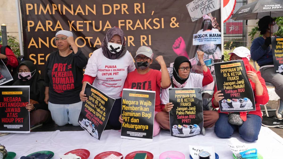 Activists hold posters and household items during a protest demanding legal protection for domestic workers outside parliament in Jakarta, photographed by AP's Tatan Syuflana