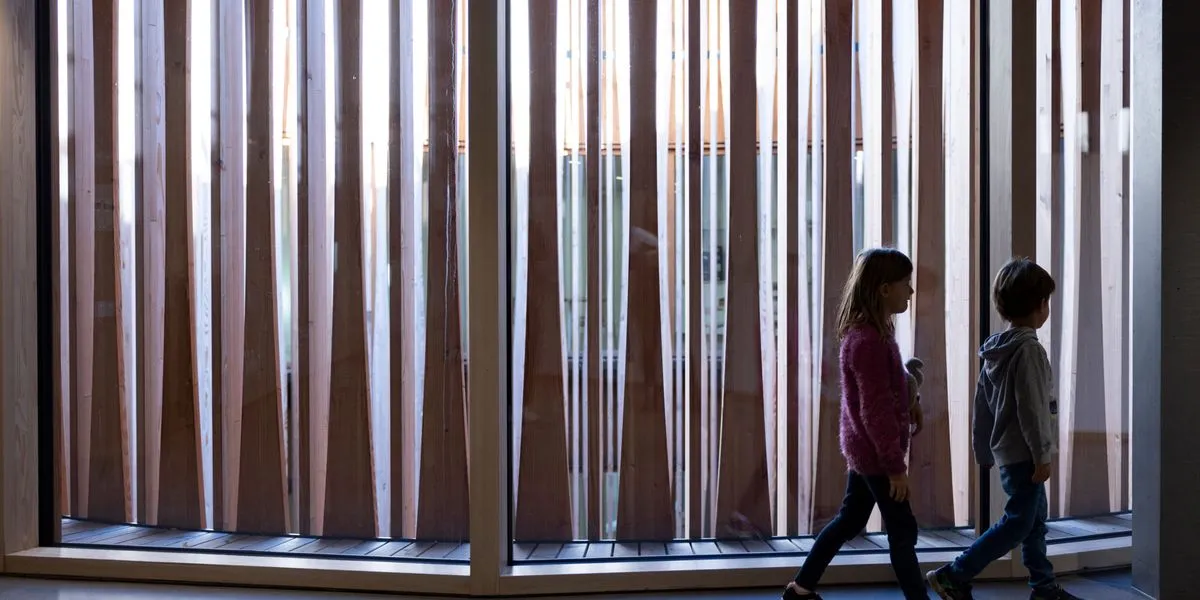 Two young patients walk through the new Zurich children's hospital building, illustrating the institution at the center of the 2025 funding and governance debate.