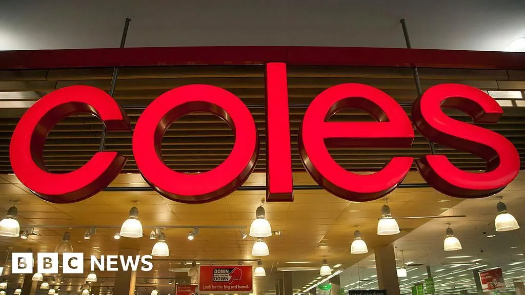 Illuminated Coles sign above the entrance of a supermarket building.