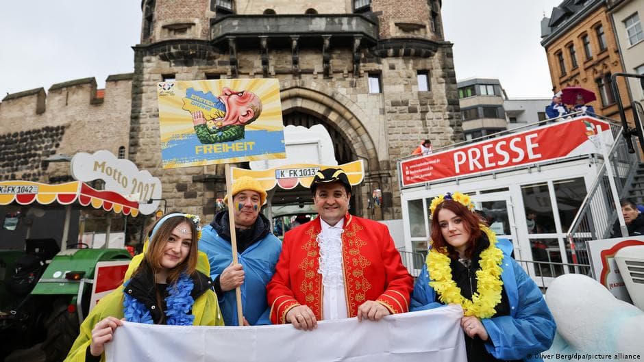 Colorful carnival floats make their way through the streets of Cologne during the 2026 Rosenmontag parade, with crowds of costumed revelers lining the route
