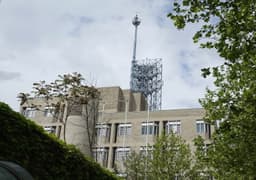 A telecommunications building with antenna equipment on its rooftop, photographed against a clear sky