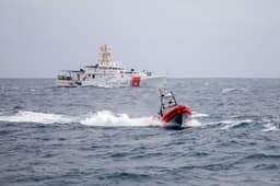A US Coast Guard vessel conducting joint operations alongside a US Navy destroyer at sea